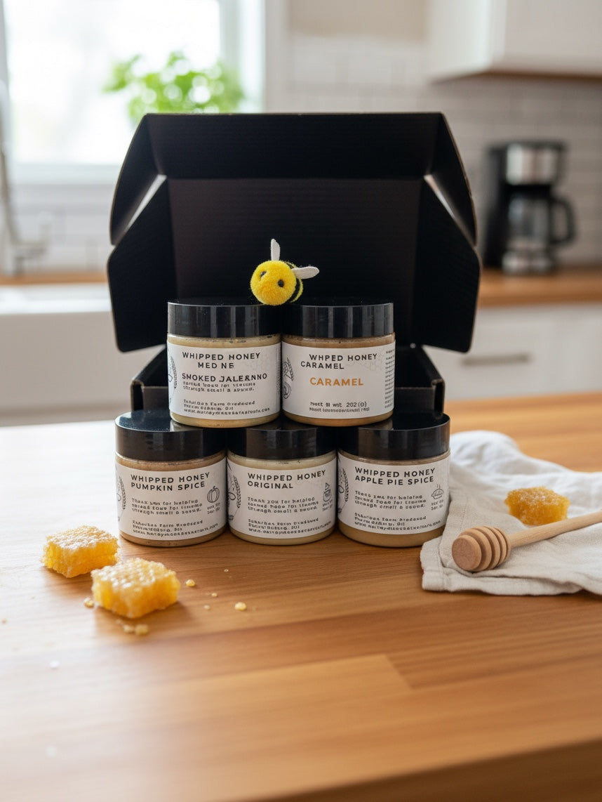Barley Moon Botanicals Autumn Indulgence whipped honey flight with five jars, honeycomb, and a felt bee on a table.