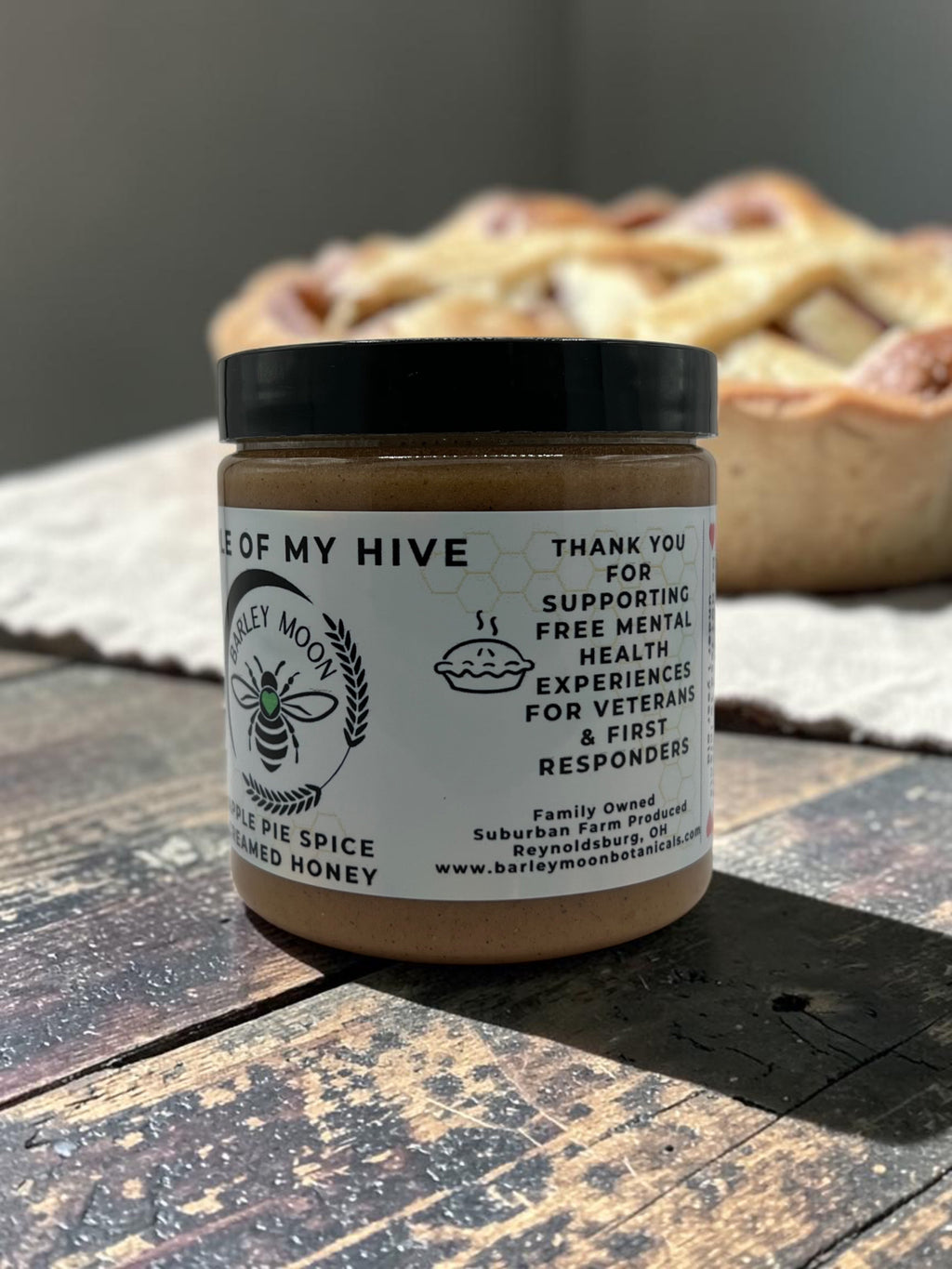 Barley Moon Botanicals Apple of My Hive creamed honey with apple pie spice in a glass jar on a rustic wooden table.