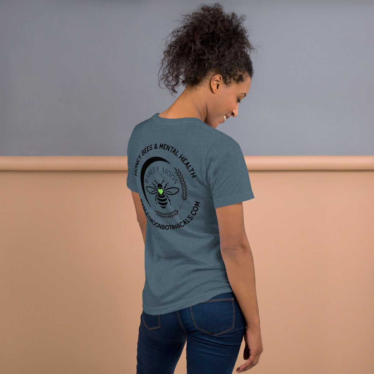 Model wearing a blue Barley Moon Botanicals t-shirt with a black bee and crescent moon logo on the back