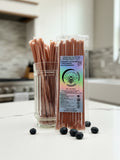 Barley Moon Botanicals blueberry creamed honey straws in a glass jar with fresh blueberries on a white kitchen counter.