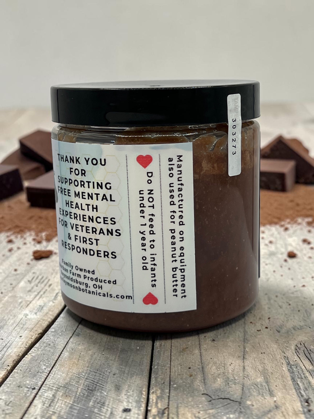 Barley Moon Botanicals Chocolicious chocolate creamed honey jar with label details on a rustic wooden surface.