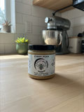 Barley Moon Botanicals Cinna-Pear creamed honey jar on a wooden kitchen counter with a stand mixer in the background.