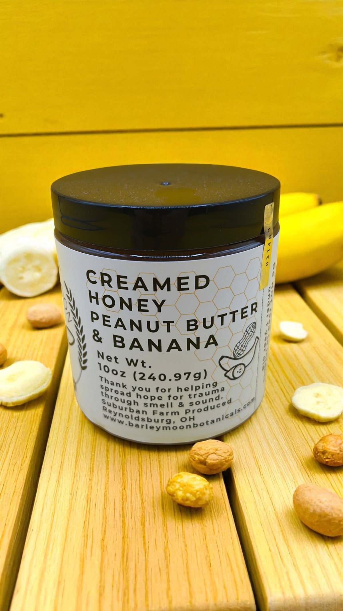 Barley Moon Botanicals Nutty Nana creamed honey jar with peanut butter and banana flavor on a yellow wooden surface.