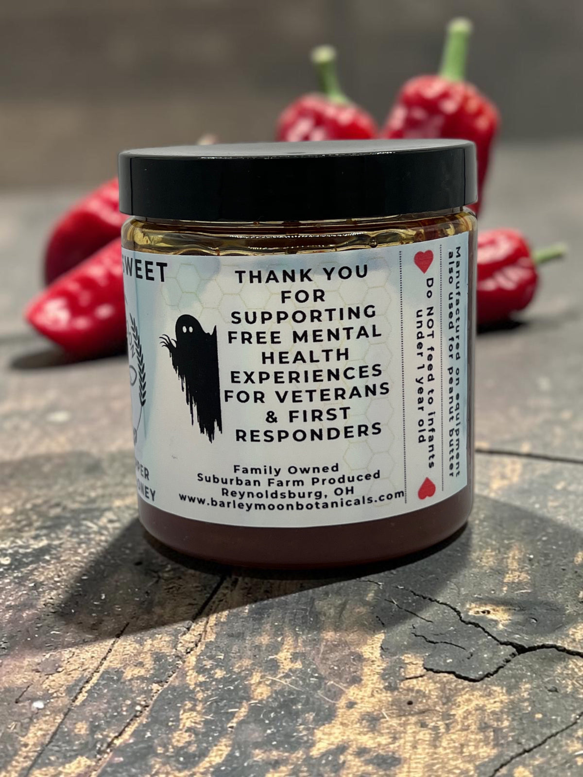 Barley Moon Botanicals Ghostly Sweet ghost pepper infused honey jar with a ghost graphic on a rustic wooden surface