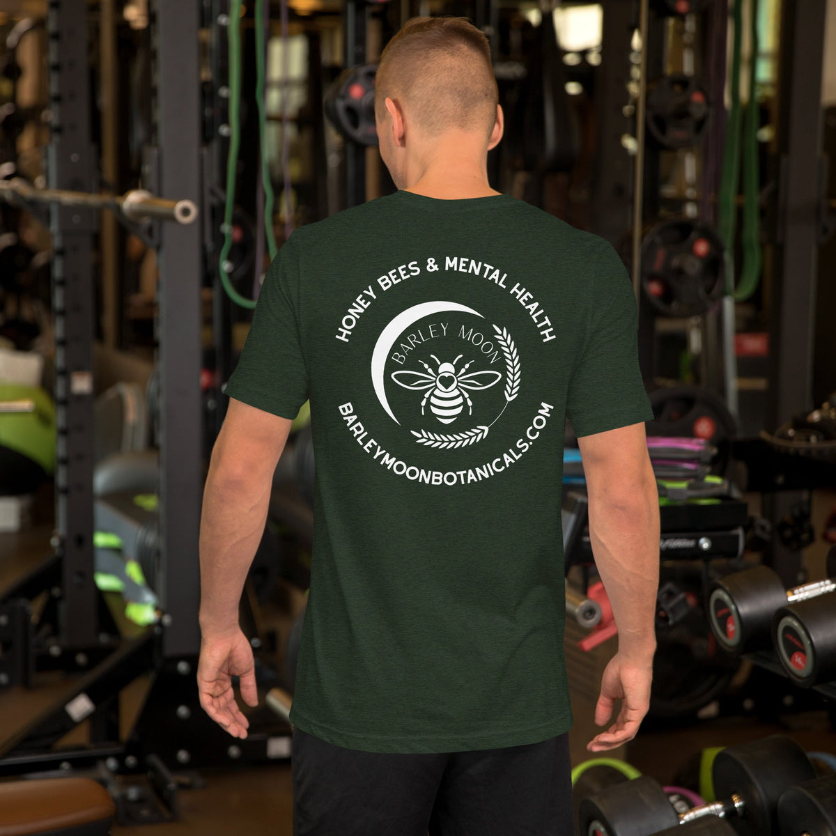 A man wearing a dark green Barley Moon Botanicals t-shirt with a white bee and crescent moon logo on the back.