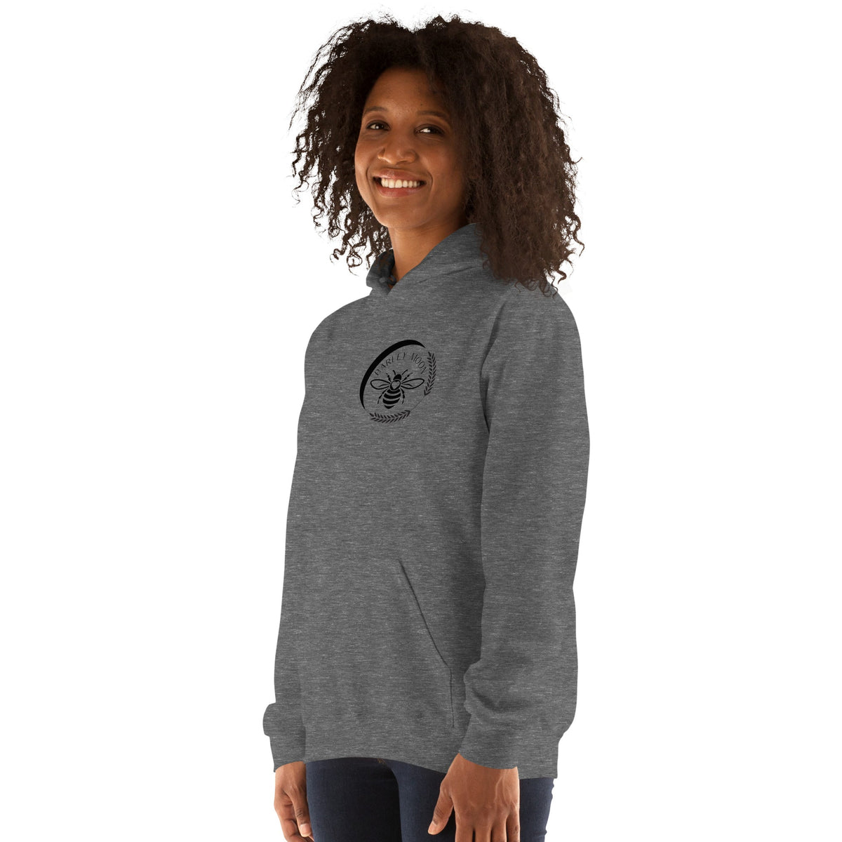A woman wearing a grey Barley Moon Botanicals unisex hoodie featuring a black bee and crescent moon logo on the chest.