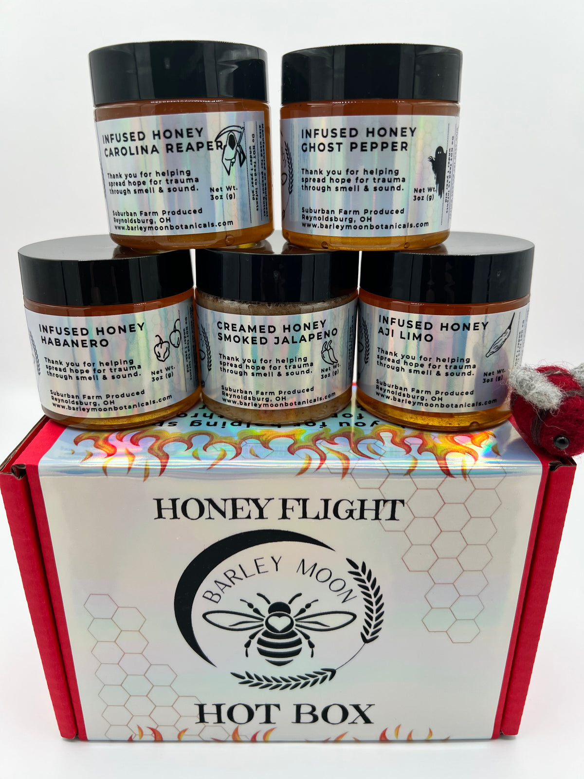 Barley Moon Botanicals Hot Box Honey Flight featuring five jars of spicy infused honey in a red gift box with a felt bee