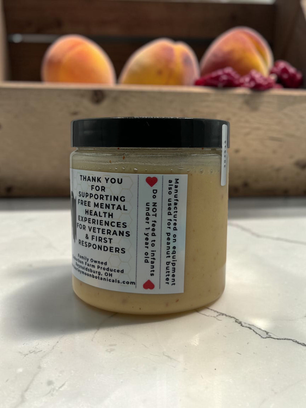 Barley Moon Botanicals Peachy Ghost creamed honey jar with peach and ghost peppers on a marble countertop