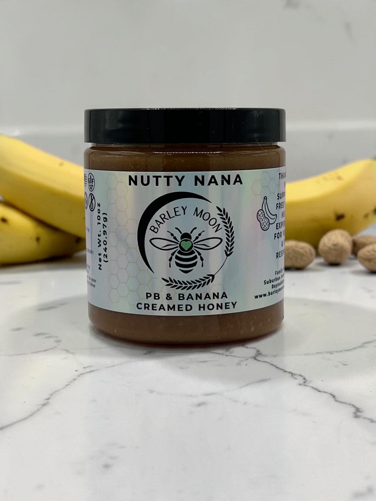 Barley Moon Botanicals Nutty Nana peanut butter and banana creamed honey in a glass jar with fresh fruit and peanuts.