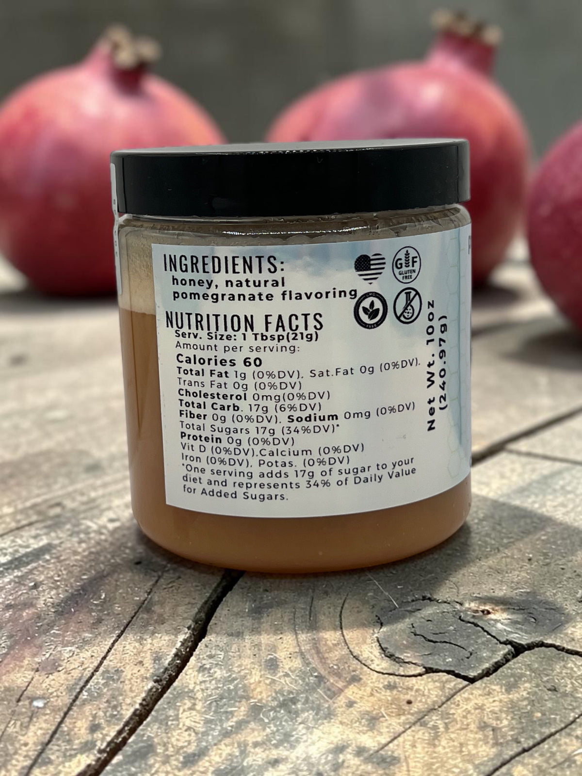 Barley Moon Botanicals Perky Pom creamed honey jar showing nutrition facts label with fresh pomegranates in background