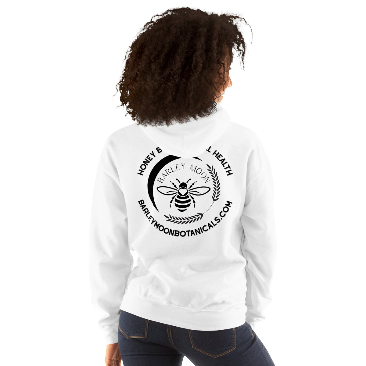 Woman wearing a white Barley Moon Botanicals unisex hoodie featuring a black bee and crescent moon logo on the back.