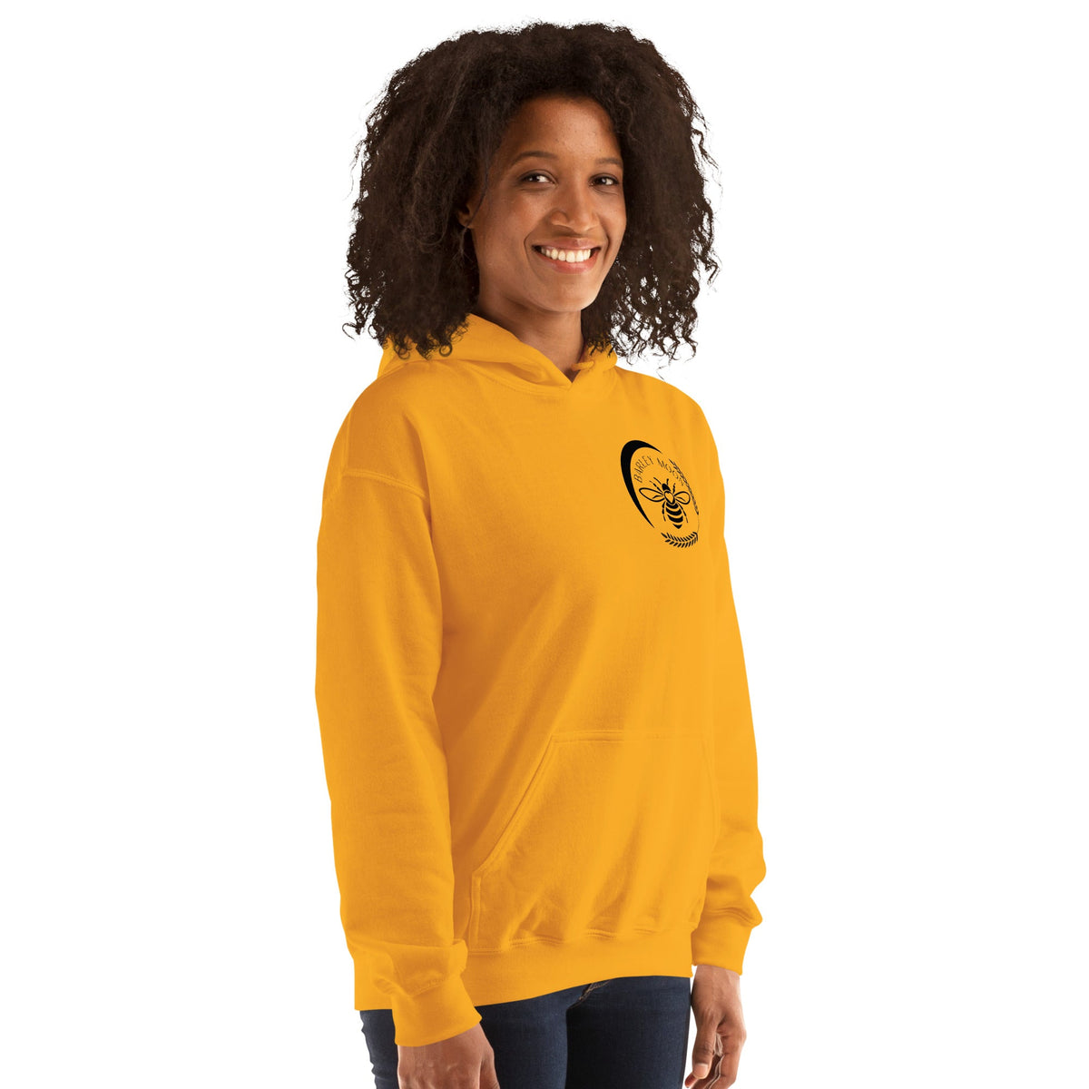 A woman wearing a bright yellow Barley Moon Botanicals unisex hoodie with a black bee and crescent moon logo.